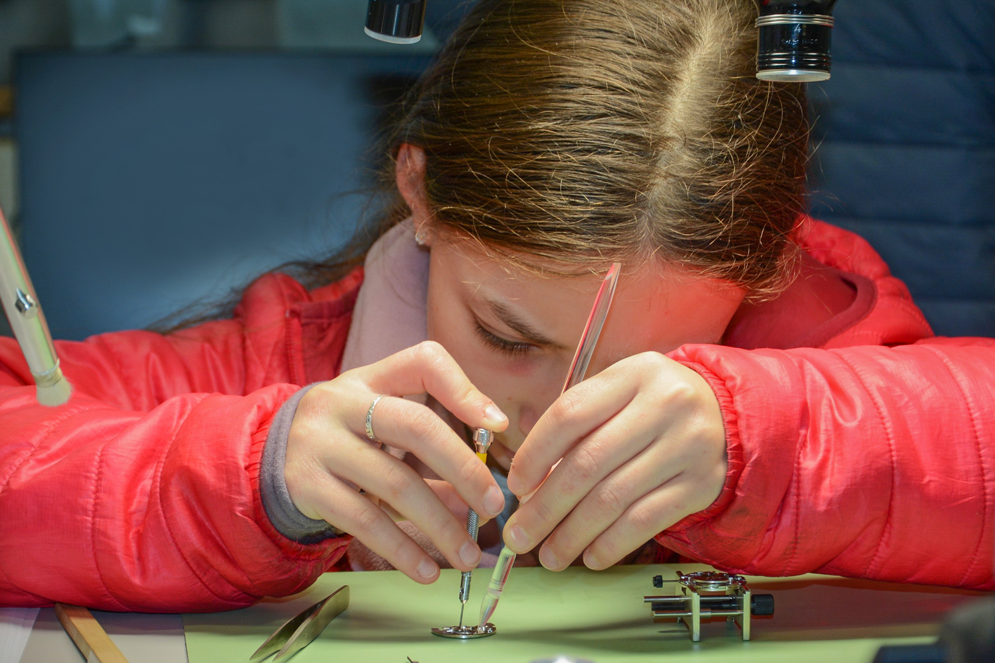 : Une jeune fille travaille sur un mouvement d'horlogerie